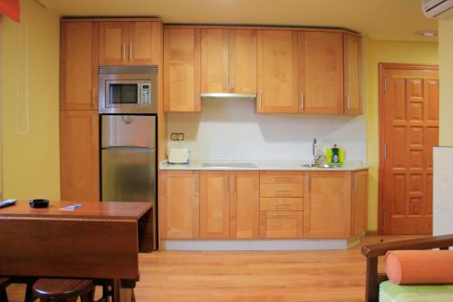 a kitchen with wooden cabinets and a wooden table at Apartamentos Ababides in Baiona