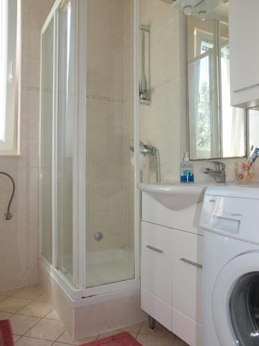 a bathroom with a shower and a sink and a washing machine at Apartment Tena in Novalja