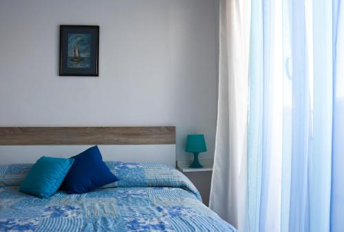a bedroom with a bed with blue pillows and a window at Apartman Moon in Zambratija