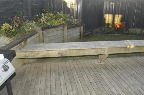 a wooden bench sitting on top of a deck at Ocean Front East End Beach House in New Plymouth