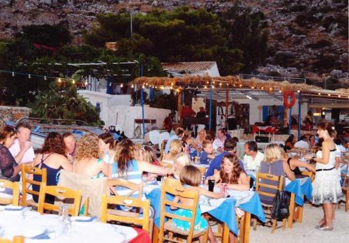 a group of people sitting at tables on a beach at La Grotta in Volimes