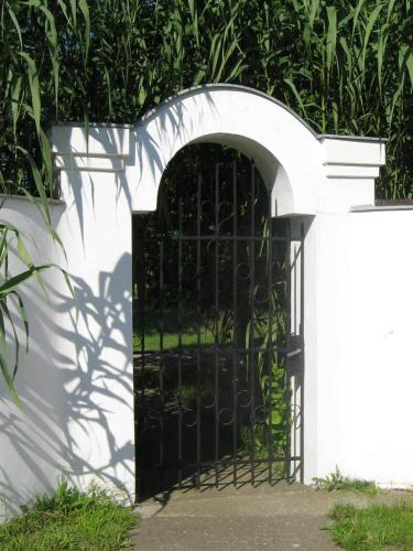 a black gate in a white wall at B&B Villa Pipacs in Feketić