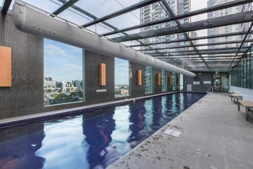 a large swimming pool in a building with windows at Nook Melbourne Apartments in Melbourne