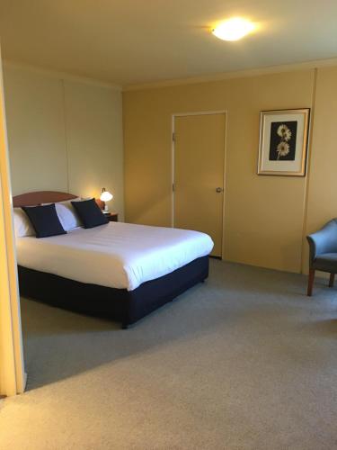 a bedroom with a large bed and a chair at Hopkins House Motel & Apartments in Warrnambool