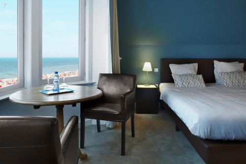 Beach Hotel في دي هان: غرفة فندقية بسرير وطاولة وكراسي