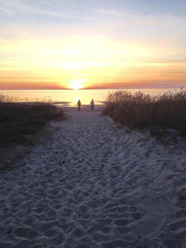 two people walking on the beach at sunset at Köpingsvik Holiday Home in Köpingsvik