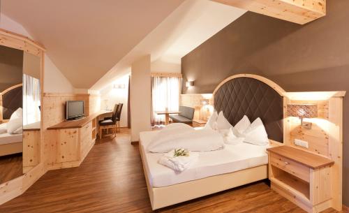 una camera d'albergo con un grande letto e una scrivania di Hotel Am Sonneck a Lagundo