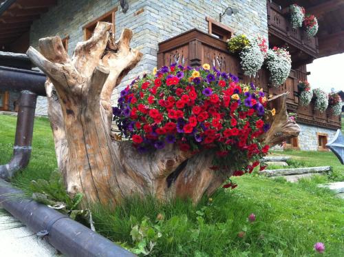 a tree stump with flowers in front of a building at Residence Lo Peyo in Champoluc