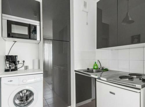a kitchen with a washing machine and a microwave at Paris Stade de France in Saint-Denis