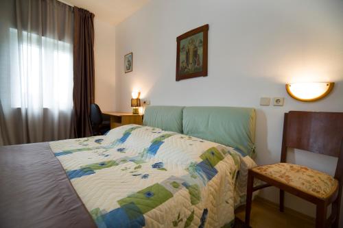 a bedroom with a bed and a chair and a window at Villa Dororeja in Veliki Drvenik