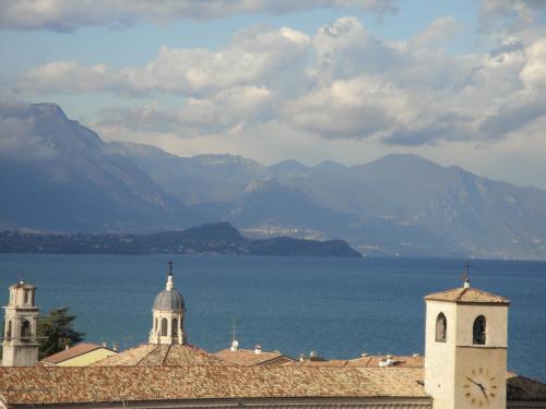 a view of a city with a clock tower and mountains at The Tower Of The Old King in Desenzano del Garda
