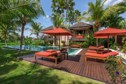 a patio with red umbrellas and a swimming pool at Villa Sabandari in Ubud
