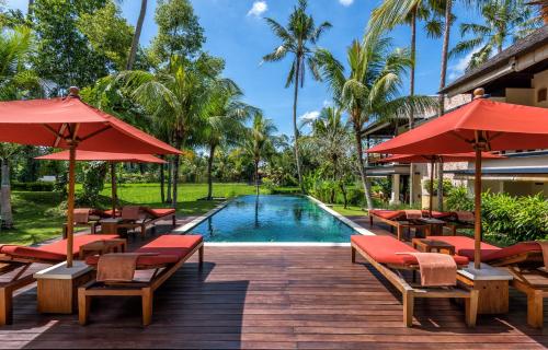 a resort with a swimming pool and red umbrellas at Villa Sabandari in Ubud