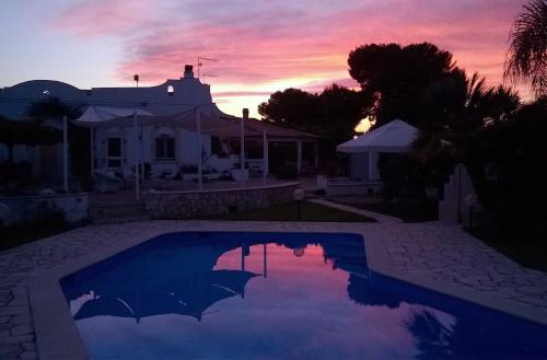 a swimming pool in front of a house with a sunset at B&B Le Vele in Maruggio