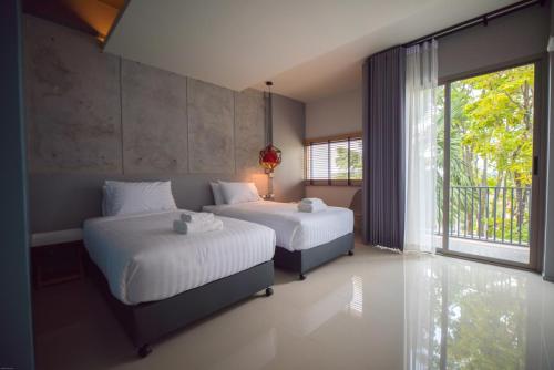 a bedroom with two beds and a large window at Wara Boutique Hotel in Udon Thani