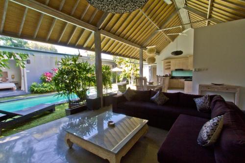 a living room with a couch and a table and a pool at VILLA Nuri Merah 1 in Kerobokan