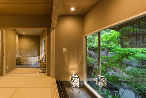 uma casa de banho com banheira e uma grande janela em Kyoto Nanzenji Ryokan Yachiyo em Quioto