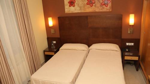a pair of beds in a room with two lamps at Hotel Macami in El Carpio