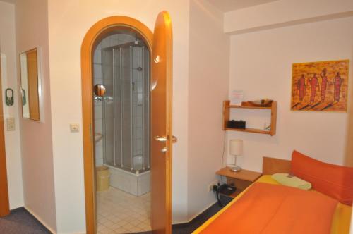 a room with an orange bed and a shower at Apart Hotel Stadtgarten in Überlingen