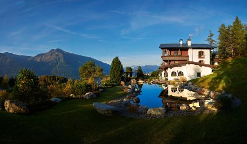 a house on a hill next to a body of water at Hotel Lärchenhof Natur in Seefeld in Tirol