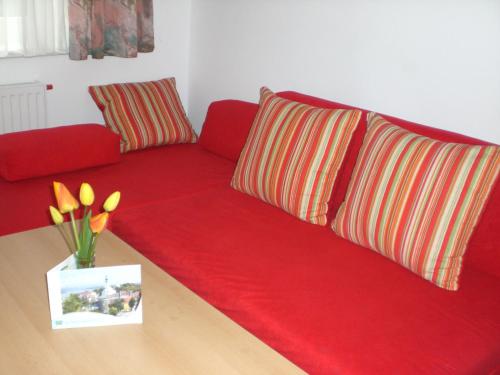 a red couch with pillows and a vase with flowers at Privatzimmer Familie Wagner in Pöchlarn