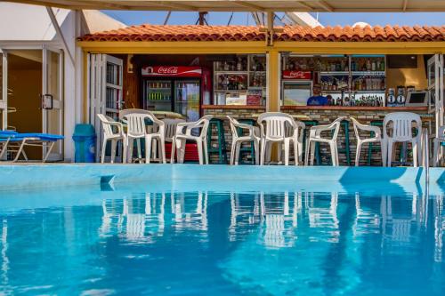 a pool of water with chairs and a bar at Paul Marie Hotel Apartments in Ayia Napa