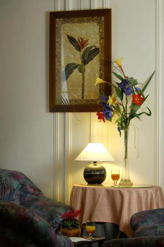 a living room with a table with a vase of flowers at Logis Le Midland in Vichy