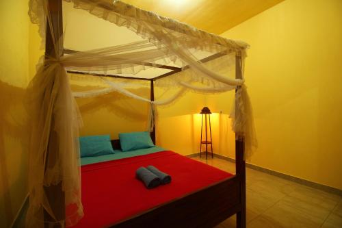 1 dormitorio con cama roja y dosel en Edy Homestay, en Munduk