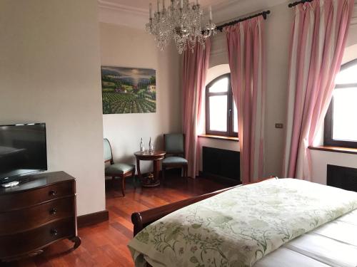 a bedroom with a bed and a television and a chandelier at Casa Palacio VillaZambra in Ronda