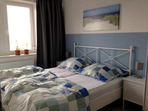 a bedroom with a bed with blue walls and a window at Ferienhaus Kiefhuck in Nordstrand