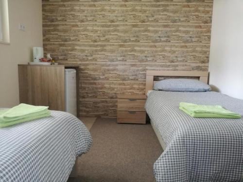 a bedroom with two beds and a brick wall at Riverside Guesthouse in Počitelj
