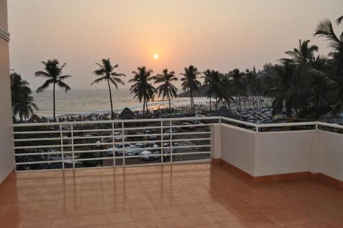a room with a view of the beach and palm trees at Marine Palace Beach Hotel in Kovalam