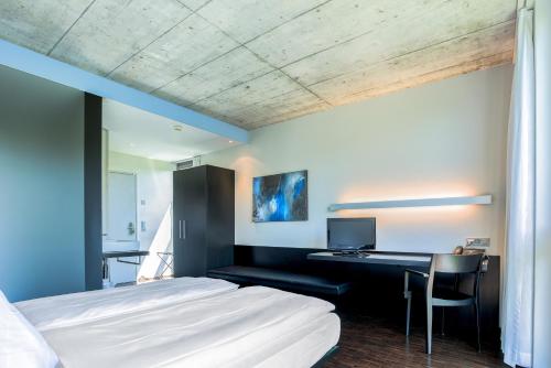Schlafzimmer mit einem Bett und einem Schreibtisch mit einem Computer in der Unterkunft Hotel Kreuzlingen am Hafen in Kreuzlingen