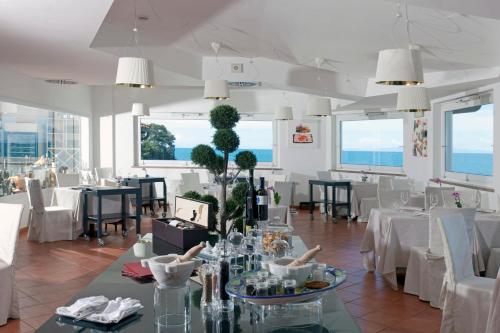 a restaurant with white tables and chairs and windows at Hotel Villa Domizia in Porto Santo Stefano