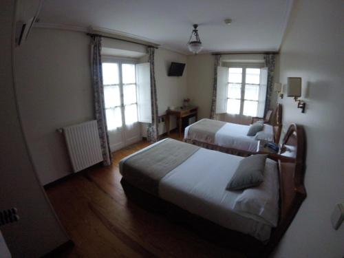 a hotel room with two beds and two windows at Hotel Asturias in Gijón