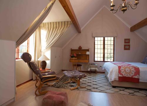 een slaapkamer met een bed, een stoel en een bureau bij Meadows Mountain View in Hout Baai