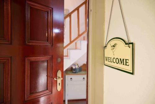 a door with a welcome sign hanging on a wall at Meadows Mountain View in Hout Bay
