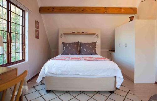 a bedroom with a white bed in a room with windows at Meadows Mountain View in Hout Bay