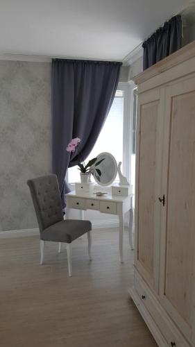 Zimmer mit einem Schreibtisch, einem Stuhl und einem Spiegel in der Unterkunft Apartment in Flensburg