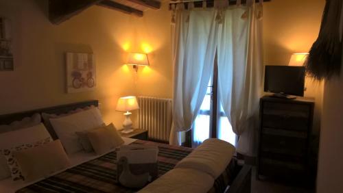 Schlafzimmer mit einem Bett, einem TV und einem Fenster in der Unterkunft Piccolo Relais Galletto di Marzo Spa e relax solo per due in Paciano