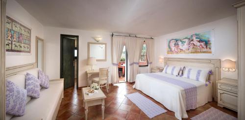 1 dormitorio con cama blanca y sofá en I Giardini di Cala Ginepro Hotel Resort, en Cala Liberotto
