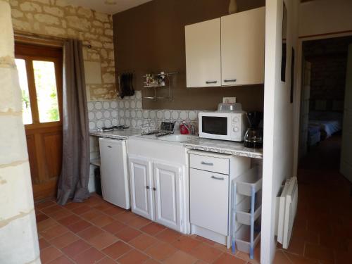 a kitchen with white cabinets and a microwave at Les Caves in Ambillou-Château