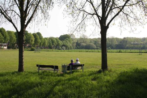 two people sitting on a park bench in a field at Hotel Restaurant Clemens-August in Ascheberg