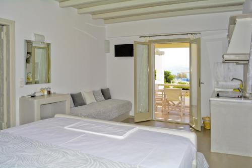 a white bedroom with a bed and a balcony at Notos Studios in Schinoussa