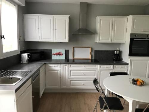 a kitchen with white cabinets and a white table at Gite du Crinchon in Rivière