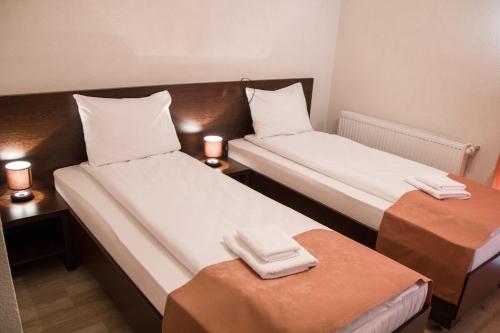 2 camas en una habitación pequeña con 2 mesas en Pensiunea Casa din Vii, en Şeuşa