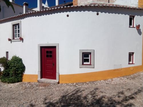 a white building with a red door and windows at Charming House Óbidos in Óbidos