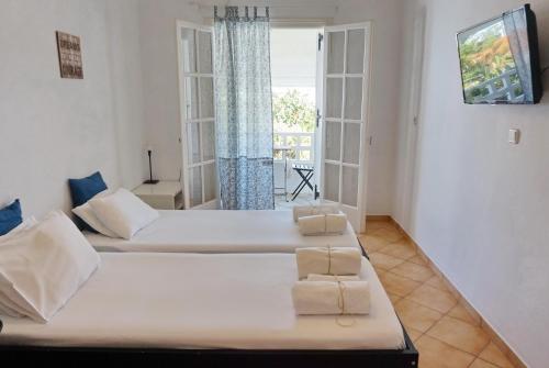 two beds in a room with a window at Ilios in Skala