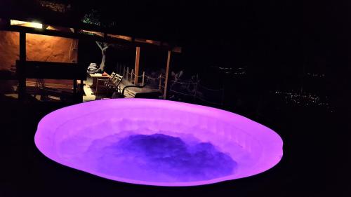 ベガ・デ・サン・マテオにあるViuter Rural Cave House El Refugio de Miguelの暗い部屋(紫のバスタブ、テーブル付)