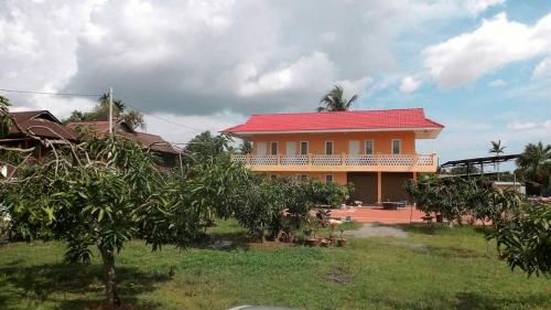a house with a red roof and a yard with trees at Harum Manis Country House in Kangar